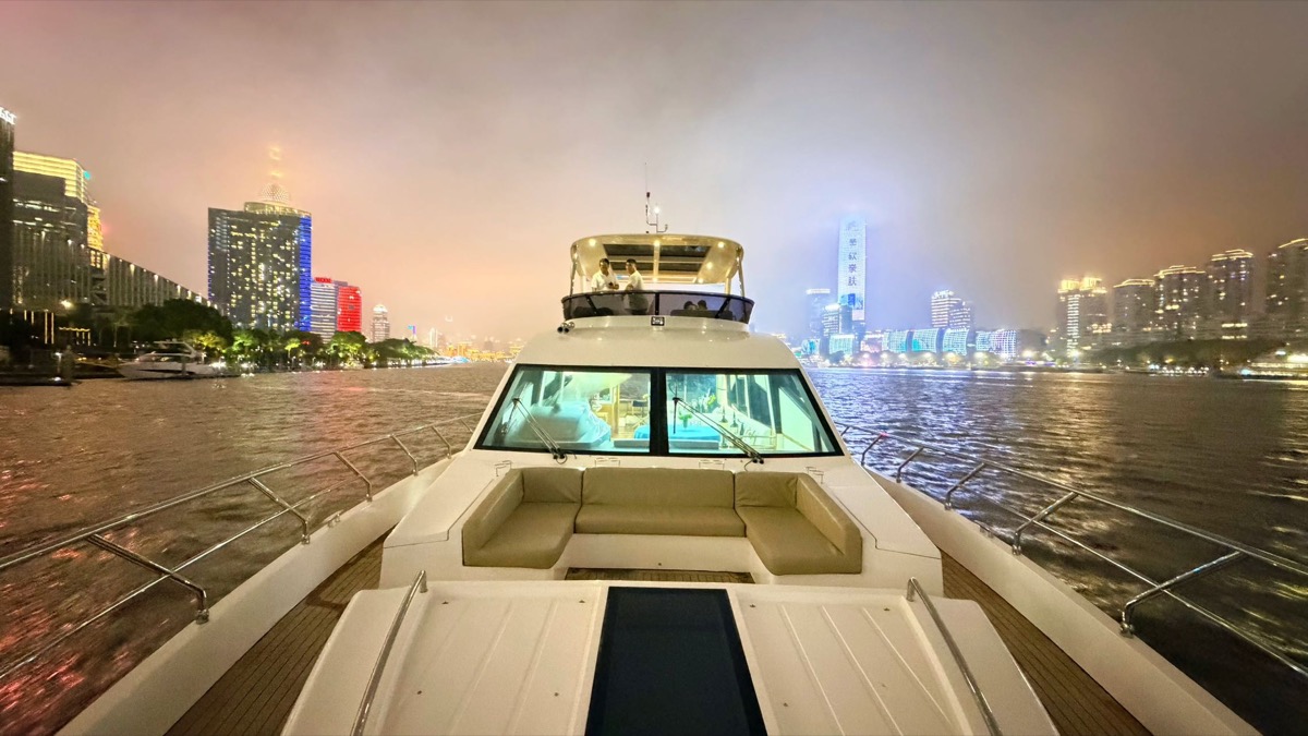 View from a private yacht bow toward the cabin and Shanghai skyline at night