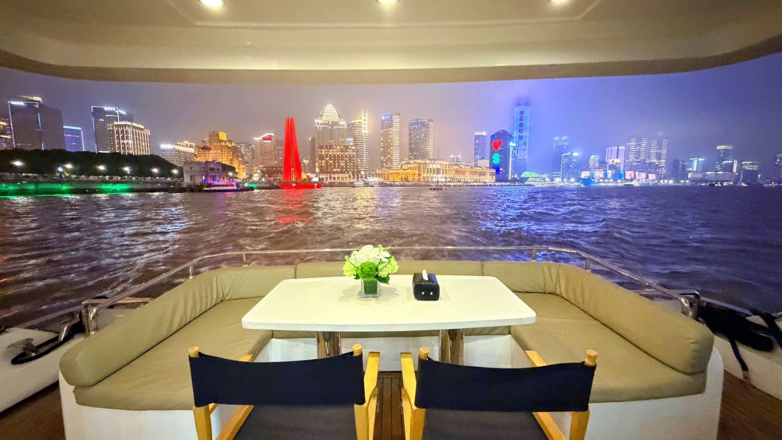 Outdoor seating on the classic yacht with Shanghai’s illuminated waterfront beyond